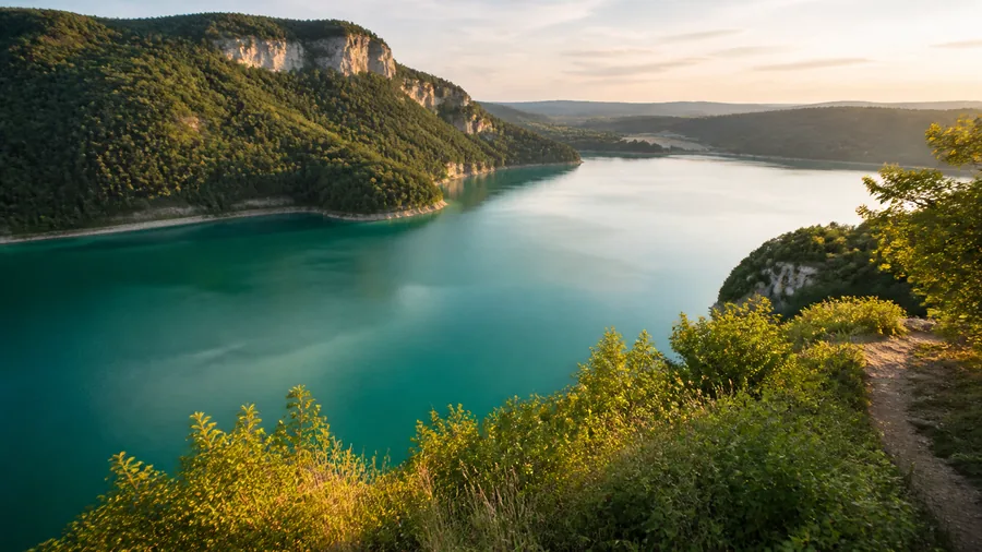 Ambiance romantique inspirée du lac de Vouglans avec eau émeraude, falaises boisées et belvédère calme