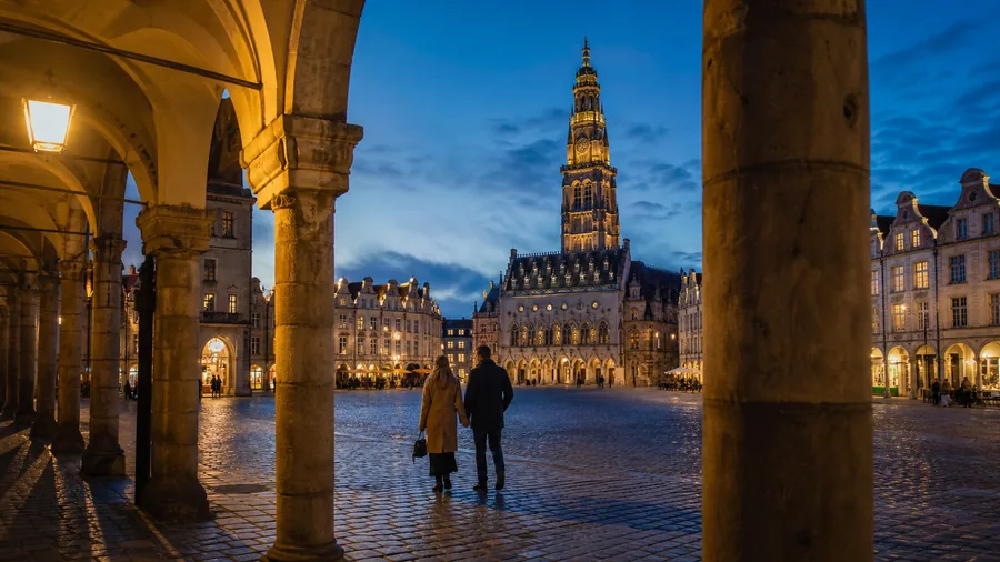 Ambiance romantique inspirée d'Arras avec arcades flamandes, beffroi éclairé et pavés de la Grand-Place